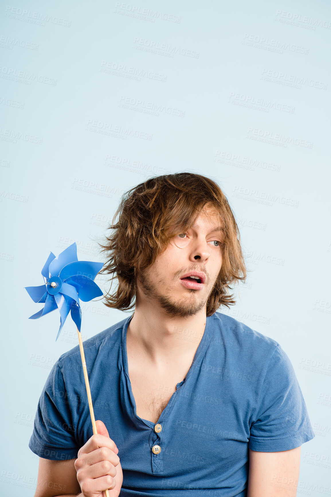 Buy stock photo Bored, pinwheel and man in studio with toy isolated on blue background space. Energy, windmill and childish person play with plastic origami fan for fashion, thinking or tired of dull game on holiday