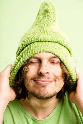 Buy stock photo Happy, hat and face of man on green background with stylish, trendy accessory and winter clothes. Eyes closed, smile and isolated person with beanie in studio for confidence, pride and comfort