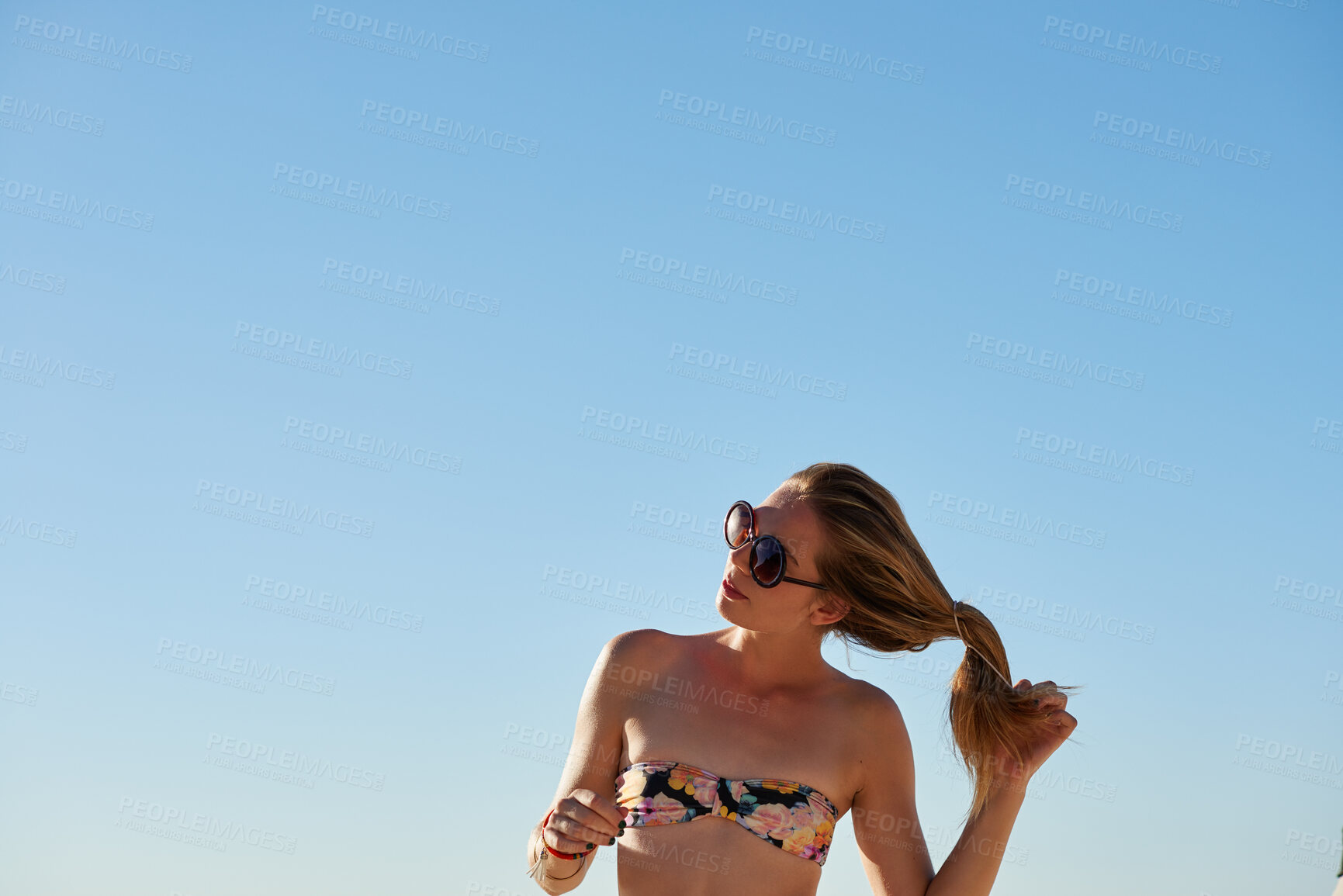 Buy stock photo Shot of a young woman untying her hair at the beach