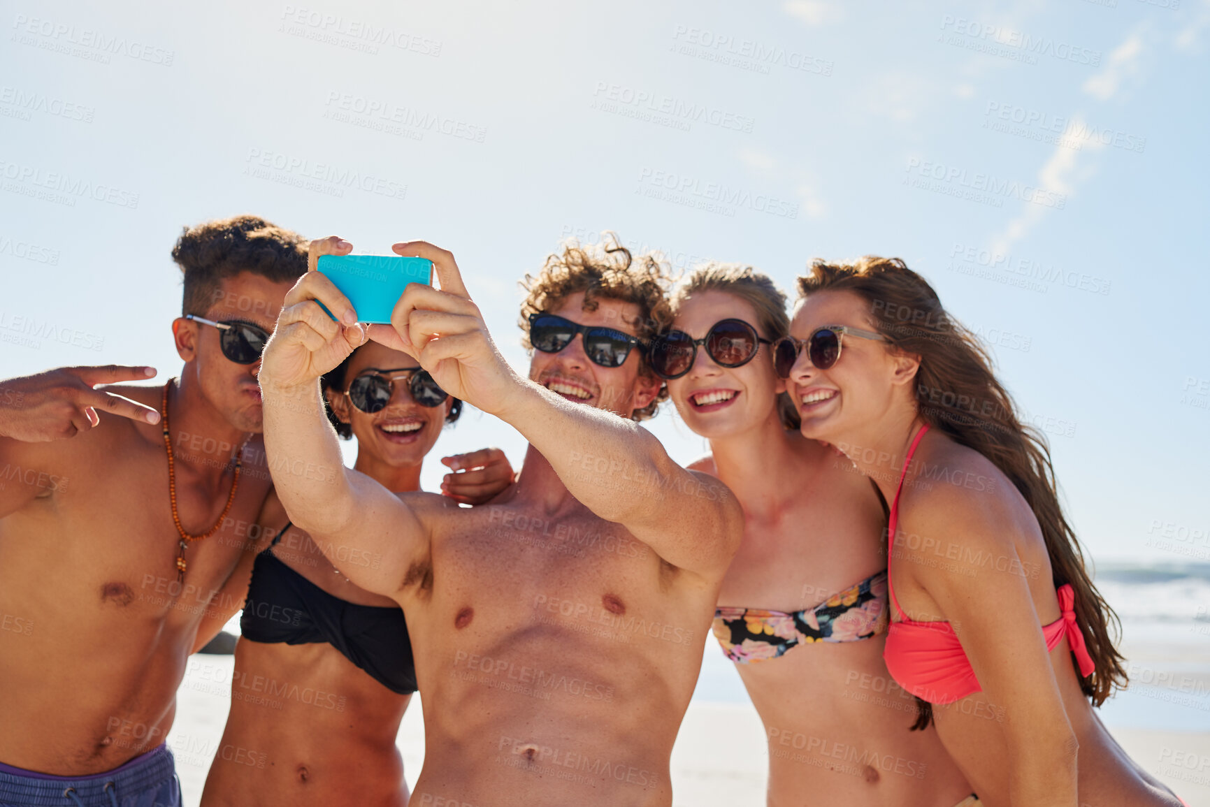 Buy stock photo Shot of a group of friends taking selfies on the beach