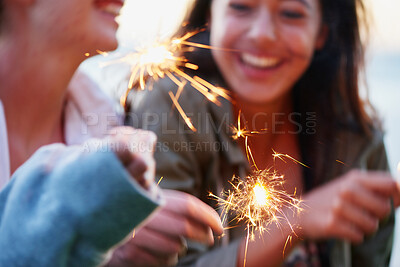 Buy stock photo Sparkle, celebration and girl friends at outdoor beach party for New Year, happy birthday or travel adventure together. Holiday festival, lights and women at event with fireworks, smile and bonding