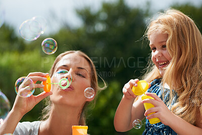 Buy stock photo Mother blowing bubbles with daughter, happiness outdoor with bonding and love with childhood and parenting. Woman playing outside with young girl, mom and female child with fun activity together