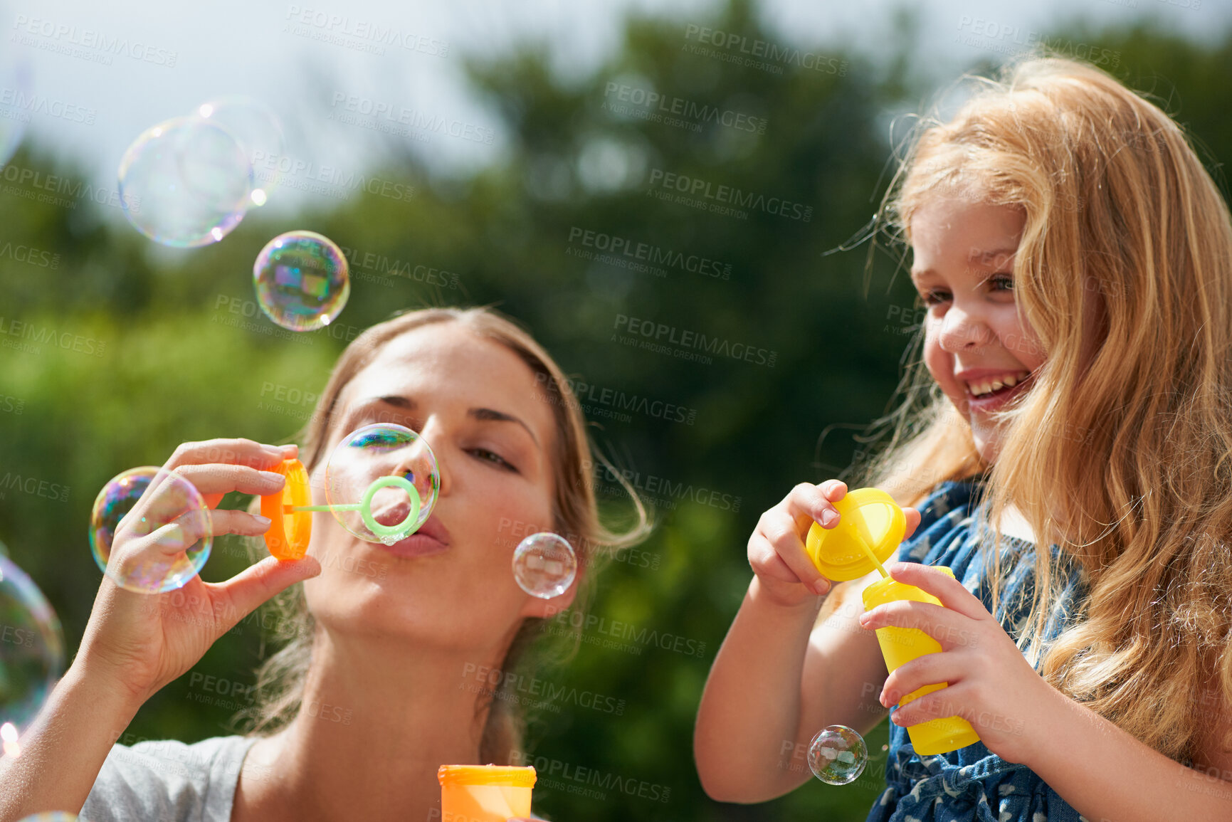 Buy stock photo Mother blowing bubbles with daughter, happiness outdoor with bonding and love with childhood and parenting. Woman playing outside with young girl, mom and female child with fun activity together