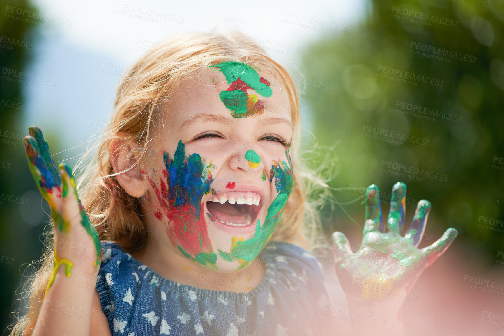 Buy stock photo Happy, little girl covered in paint and outdoors with a lens flare. Happiness or creative, playing or art fun and cheerful or excited young child with painting over her face outside in the summer