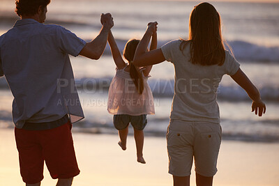 Buy stock photo Playing, child and parents holding hands on beach for fun, travel holiday and bonding together on summer adventure. Mom, dad and girl on family vacation with ocean sunset, support and waves from back