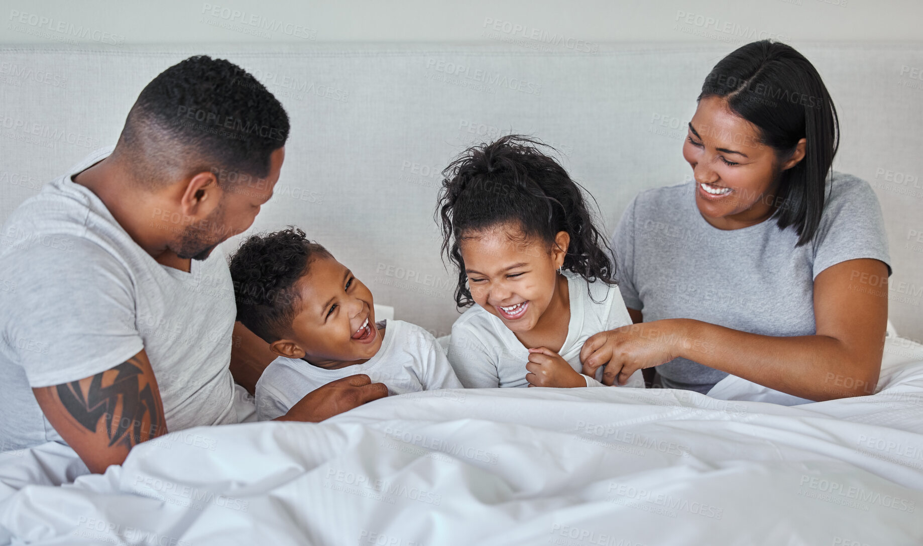 Buy stock photo Family, happy and parents tickling in bed with children for bonding, love and fun at home. Man, woman and kids laugh with girl and boy in bedroom for relax, weekend rest and smile together in morning