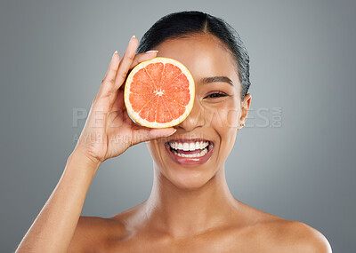 Buy stock photo Happy woman, portrait and skincare with grapefruit for vitamin C, natural cosmetics or collagen on a gray studio background. Young, female person or model with smile for organic detox or antioxidant