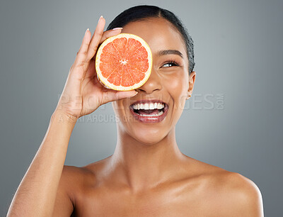 Buy stock photo Happy woman, skincare and vitamin C with grapefruit for natural cosmetics or collagen on a gray studio background. Young, female person or model with smile for organic fruit, detox or antioxidant