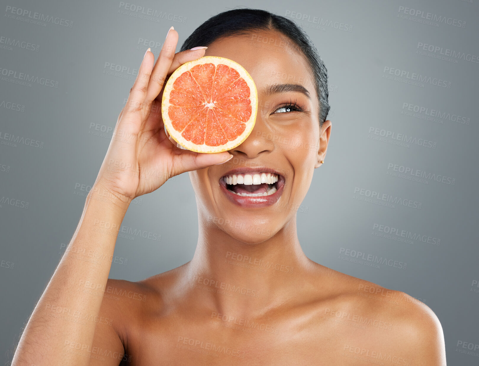 Buy stock photo Happy woman, skincare and vitamin C with grapefruit for natural cosmetics or collagen on a gray studio background. Young, female person or model with smile for organic fruit, detox or antioxidant