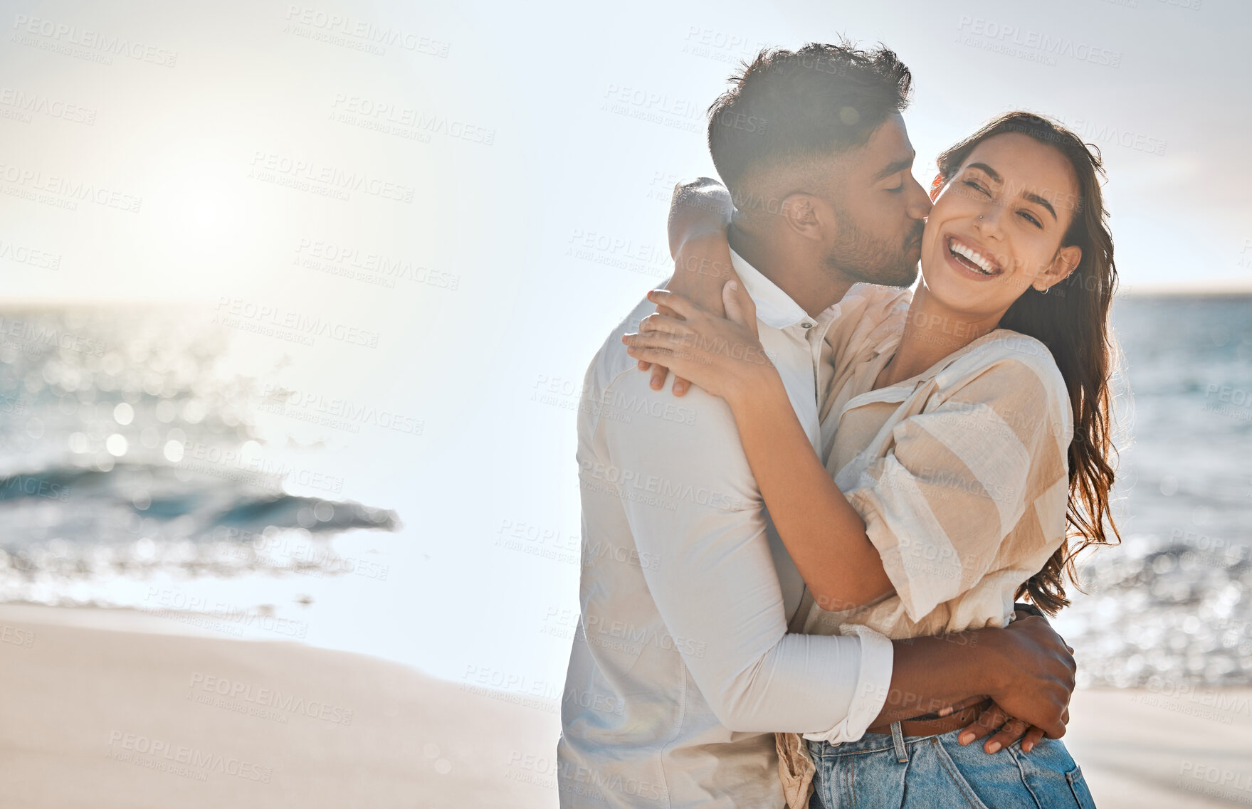 Buy stock photo Interracial, kiss or couple hug at sea for love on vacation, valentines day or holiday in Spain. Laughing, relationship and people at beach for bonding together for romantic trip on tropical island