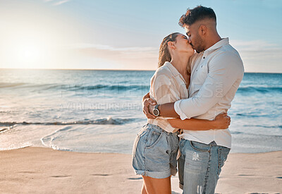 Buy stock photo Shot of a young couple kissing while spending a day at the beach