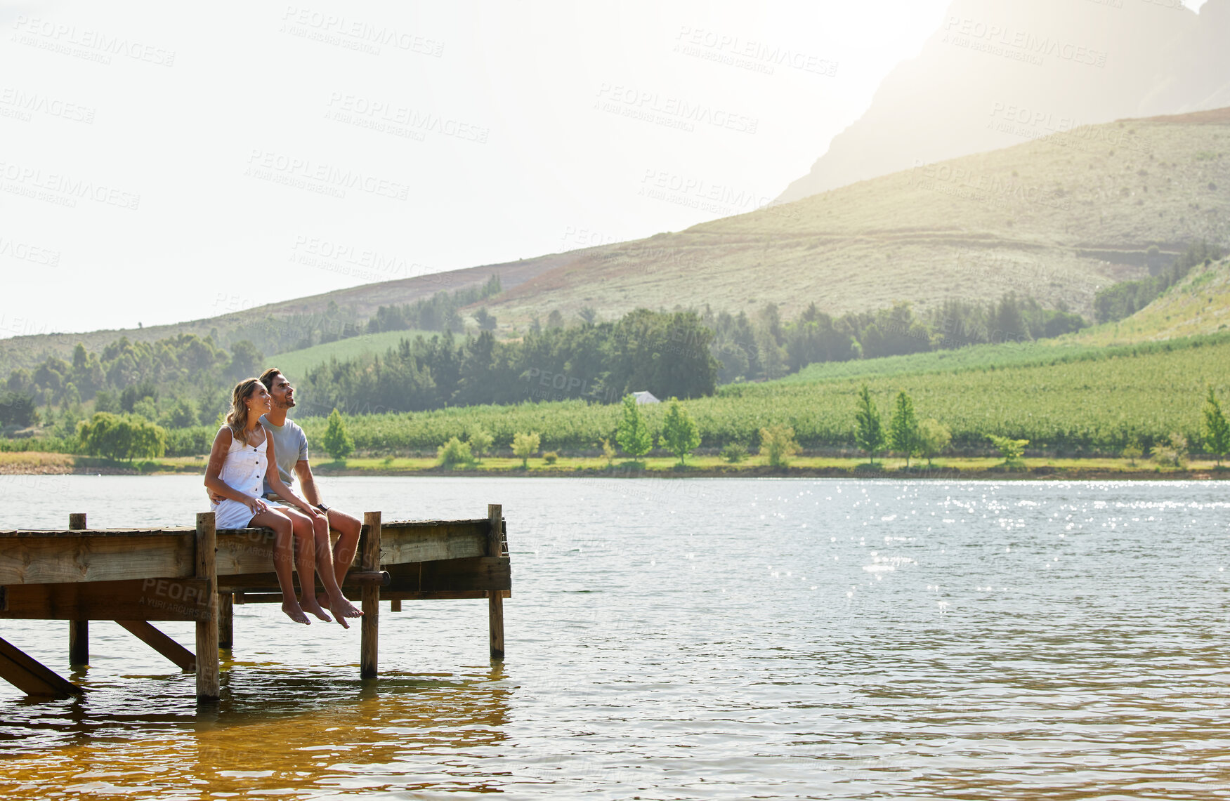 Buy stock photo Couple in nature, relax by lake and summer, travel and adventure, love and care outdoor. People in relationship, trust and bond on vacation, man and woman together sitting on jetty, freedom and view