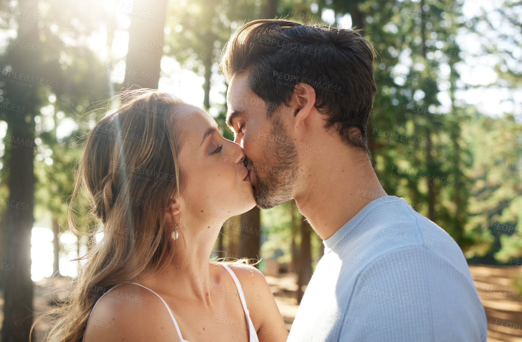 Buy stock photo Couple kiss in forest, love and summer with freedom and adventure, affection in relationship and care outdoor. People together in nature park, commitment and trust with romance, content and sunshine