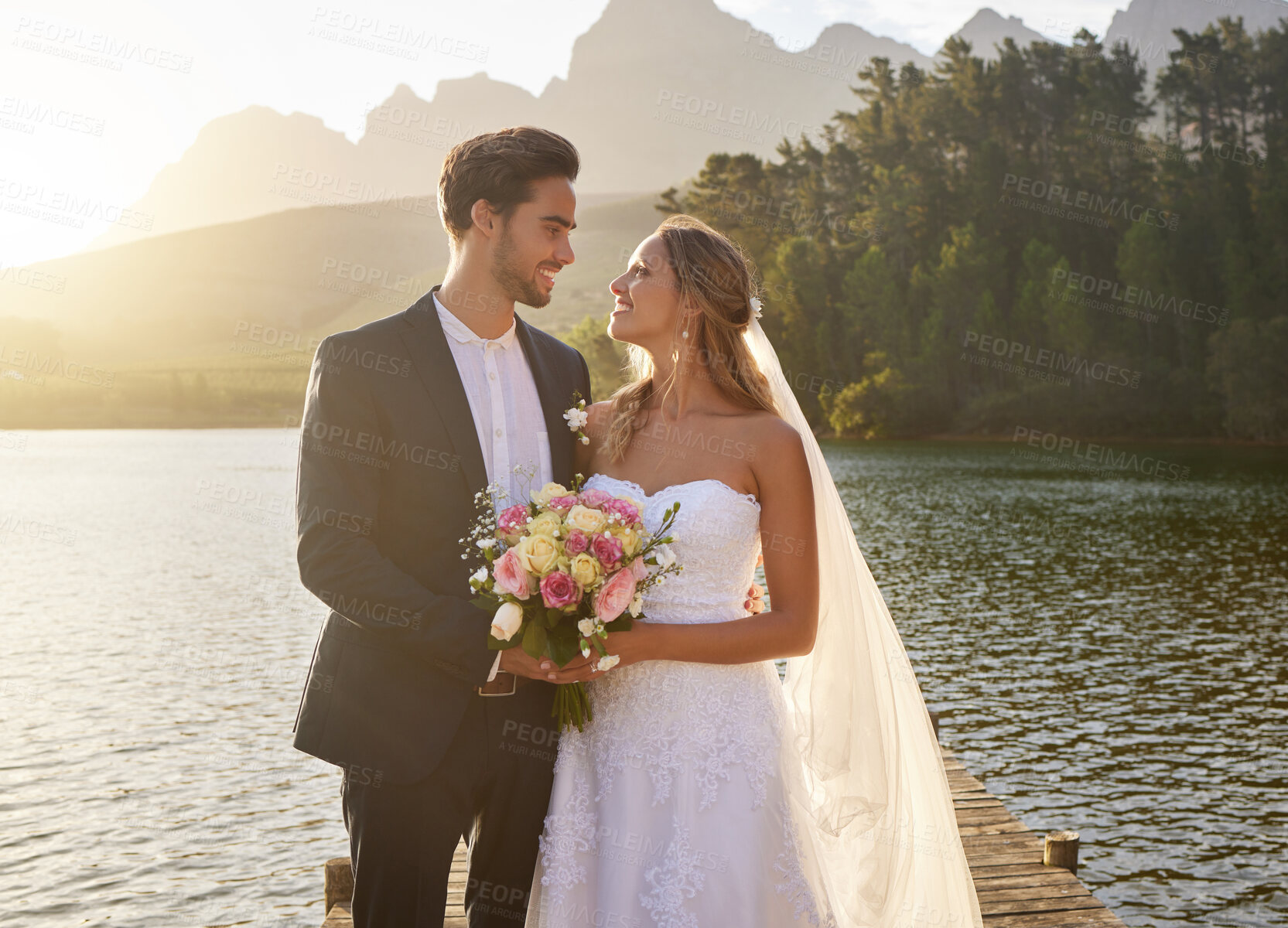 Buy stock photo Wedding, couple and lake with a bride feeling love, care and support from marriage together. Nature, happiness and relationship bond of young people with a happy smile from trust and commitment event