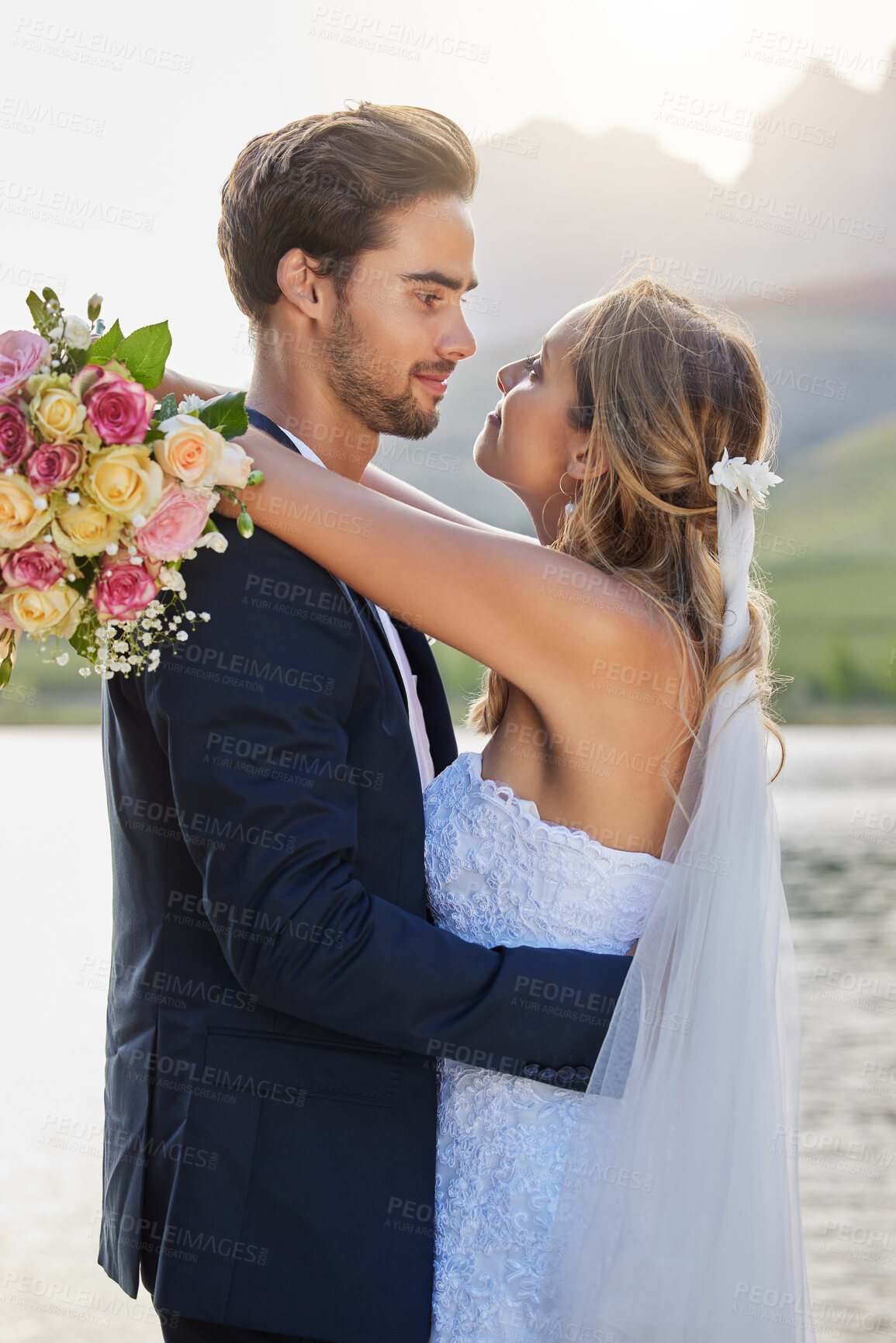 Buy stock photo Love, lake wedding and couple hug for bond commitment, romantic ceremony or union event in outdoor nature. Eye contact, flower bouquet and marriage of man, woman or fiance together in solidarity