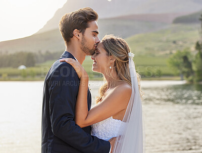Buy stock photo Love, wedding with a bride and groom kissing by a lake outdoor in celebration of their marriage for romance. Water, summer and kiss with a newlywed couple bonding together in tradition after ceremony