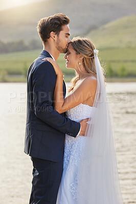 Buy stock photo Love, wedding and a couple kissing by a lake outdoor in celebration of marriage for romance as newlyweds. Water, summer or kiss with a bride and groom bonding together in tradition after ceremony