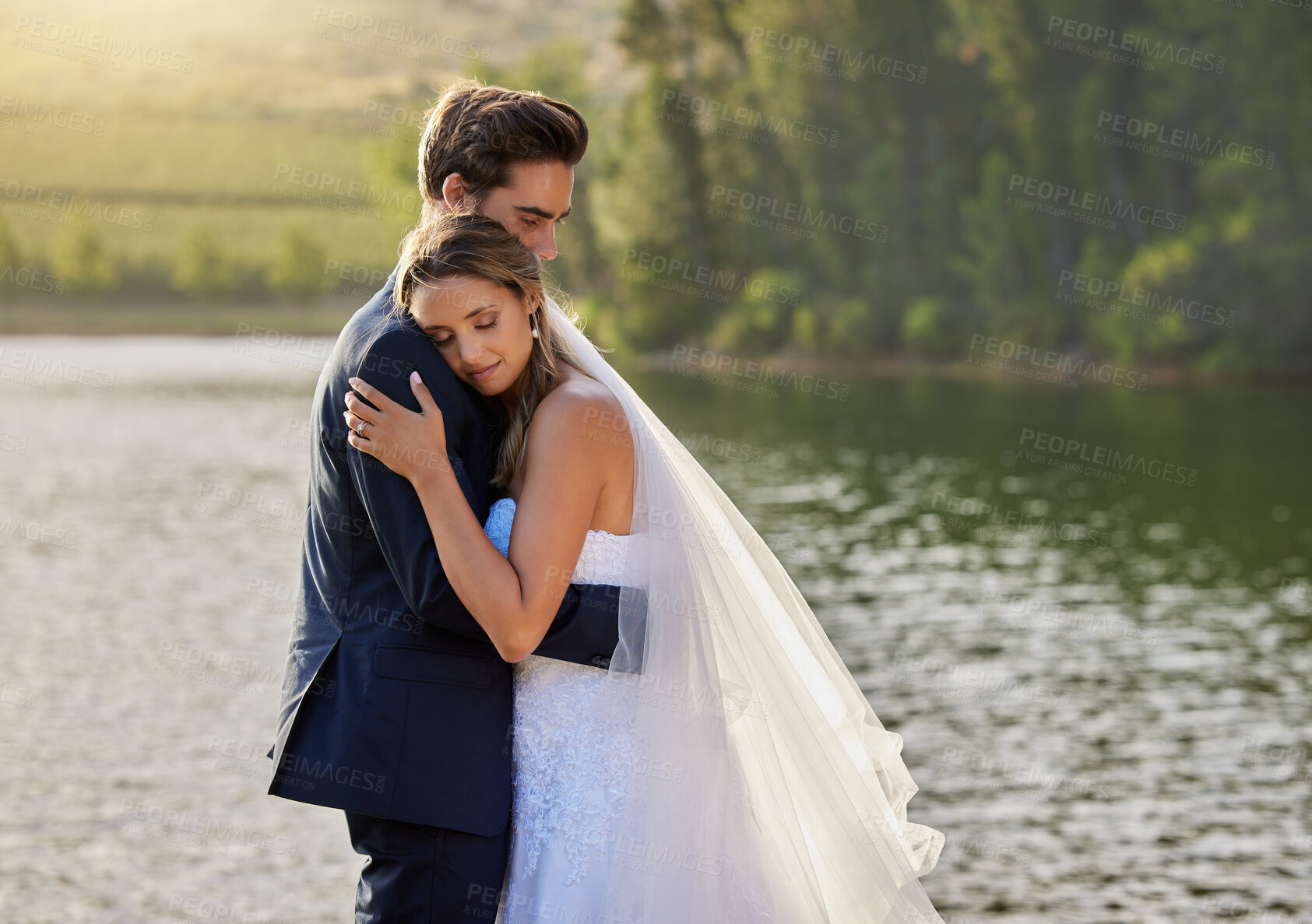 Buy stock photo Wedding couple, hug and relax by lake for love on romantic getaway or honeymoon in nature. Calm woman hugging man in happy marriage relaxing by the water together enjoying the loving embrace outdoors