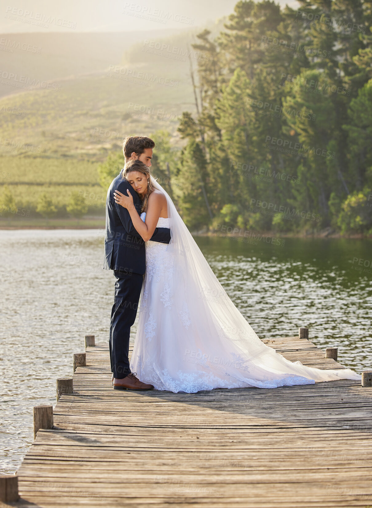 Buy stock photo Wedding couple, hug and relax by lake for honeymoon, love or romantic getaway in nature. Calm woman hugging man in happy marriage relaxing by the water together enjoying the loving embrace outdoors