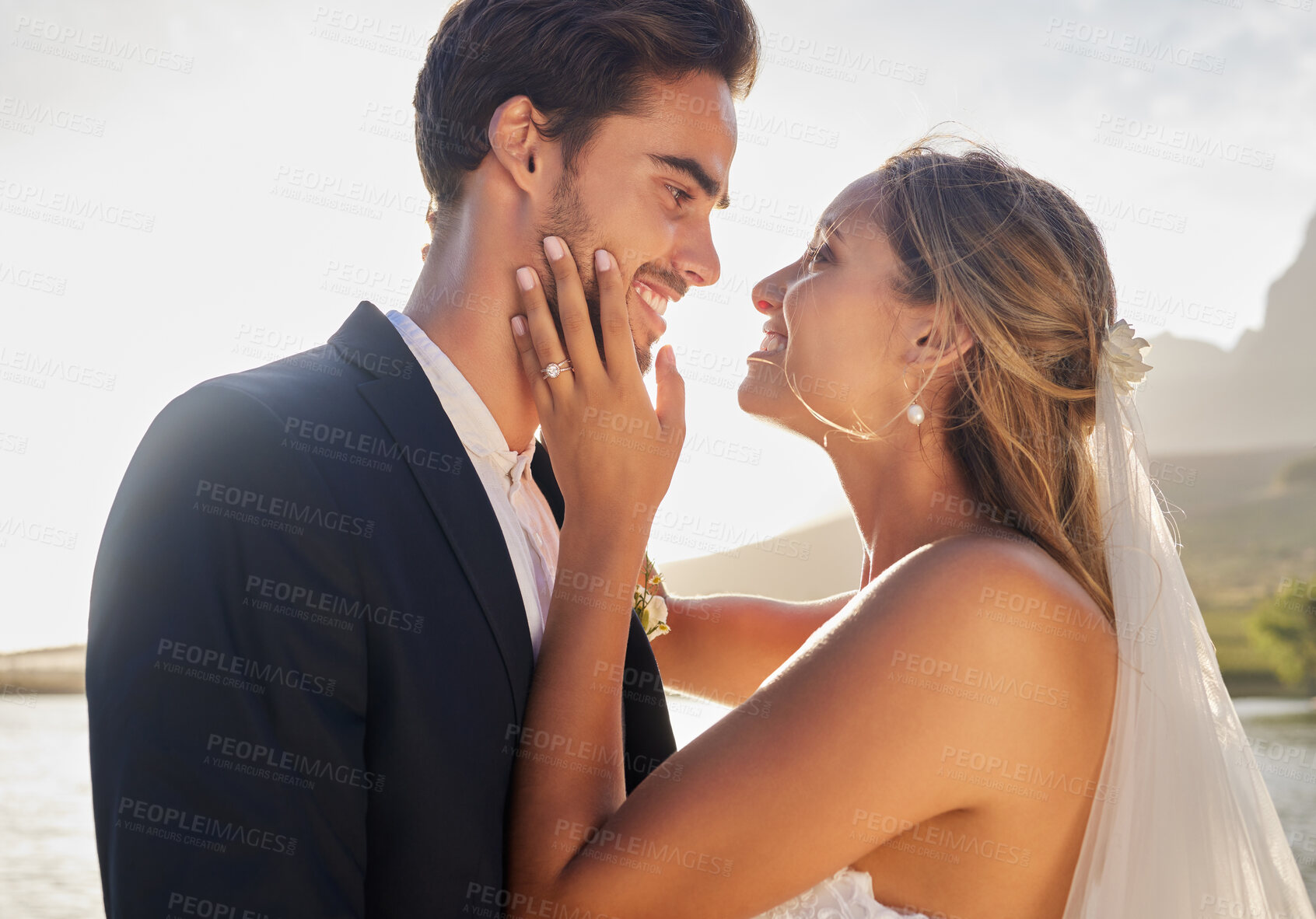 Buy stock photo Wedding, happy couple and lake with a bride feeling love, care and support from marriage together. Nature, happiness and romantic embrace of young people with a smile from trust and commitment event