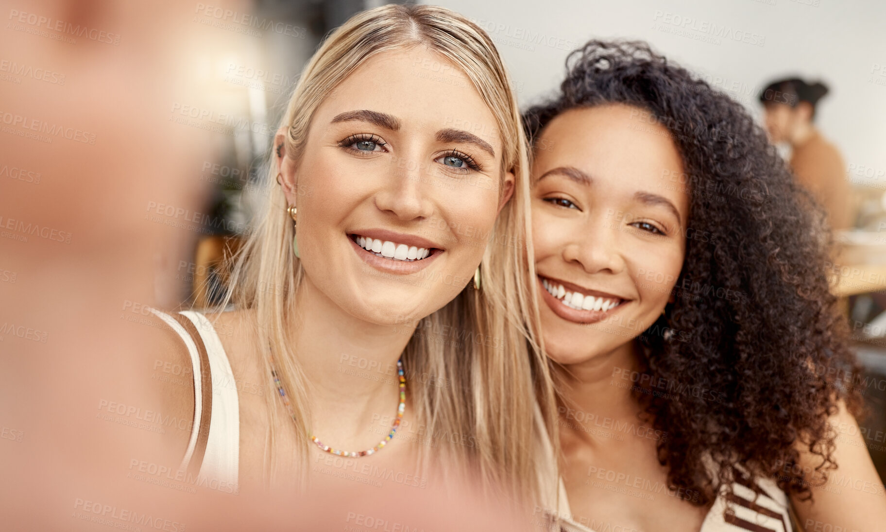 Buy stock photo Shot of two young friends taking selfies together at a restaurant