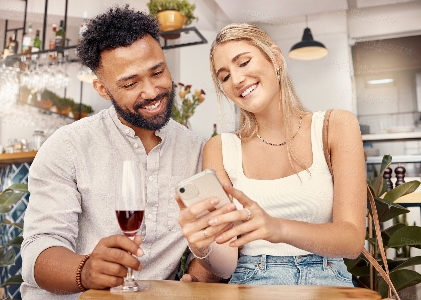 Buy stock photo Shot of a young couple using a smartphone together at a restaurant