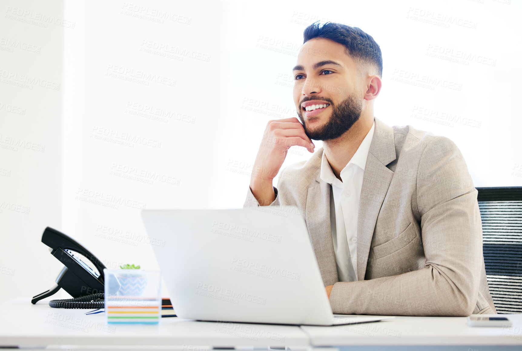 Buy stock photo Shot of a handsome young businessman sitting alone in the office and using his laptop