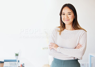 Buy stock photo Shot of an attractive young businesswoman standing alone in the office with her arms folded