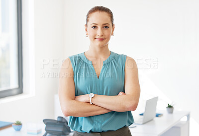 Buy stock photo Shot of an attractive young businesswoman standing alone in the office with her arms folded