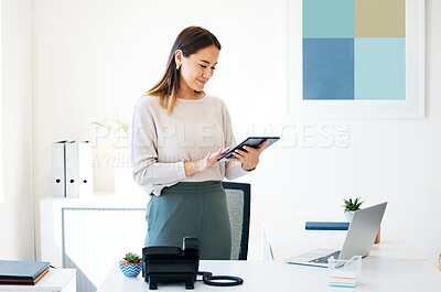 Buy stock photo Shot of an attractive young businesswoman standing alone in the office and using a digital tablet