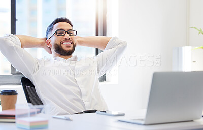 Buy stock photo Shot of a handsome young businessman sitting alone in the office with his hands behind his head and feeling successful