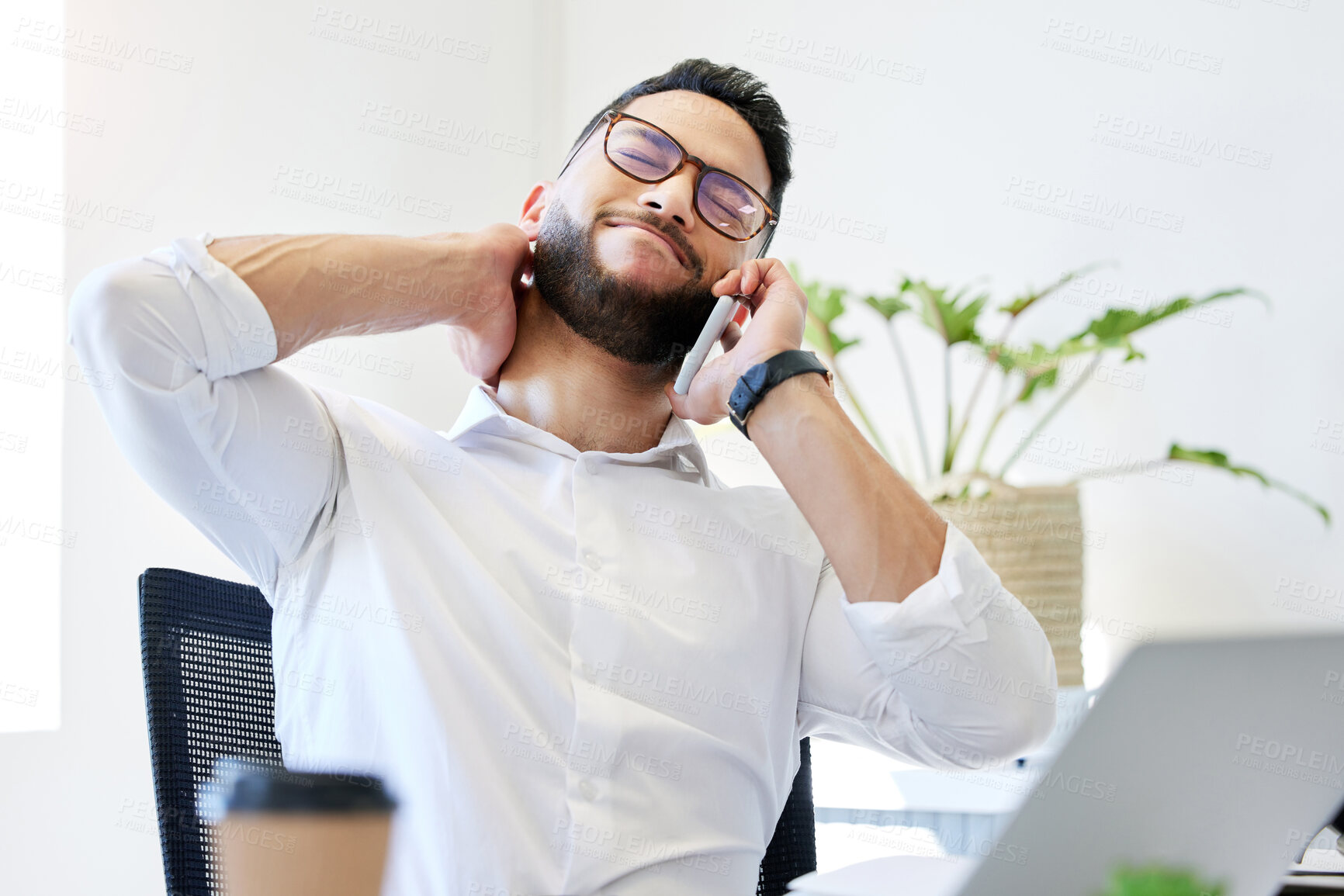 Buy stock photo Shot of a handsome young businessman sitting alone in the office and suffering from neck pain while using technology