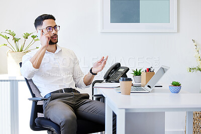 Buy stock photo Shot of a handsome young businessman sitting alone in the office and using his cellphone