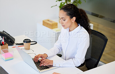 Buy stock photo Shot of an attractive young businesswoman sitting alone in the office and looking contemplative while using her laptop