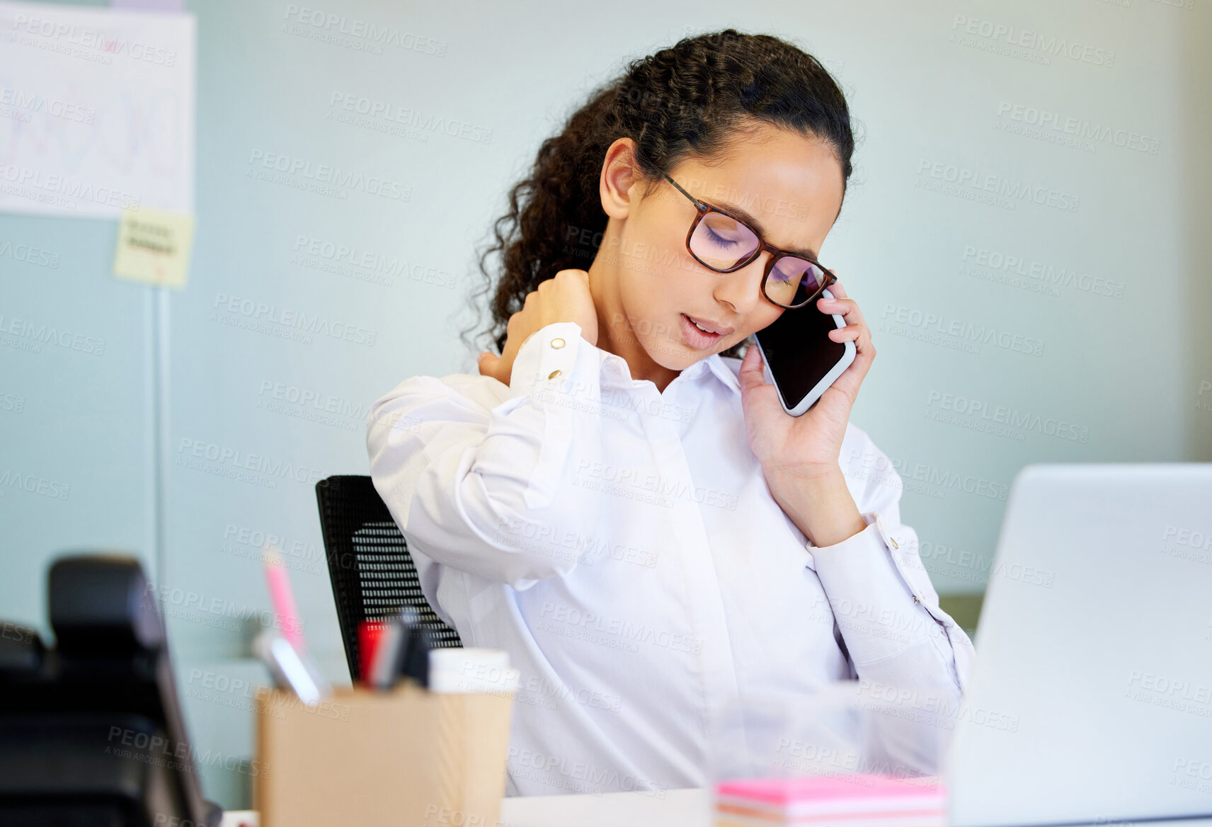 Buy stock photo Shot of an attractive young businesswoman sitting alone in the office and suffering from neck pain while using technology