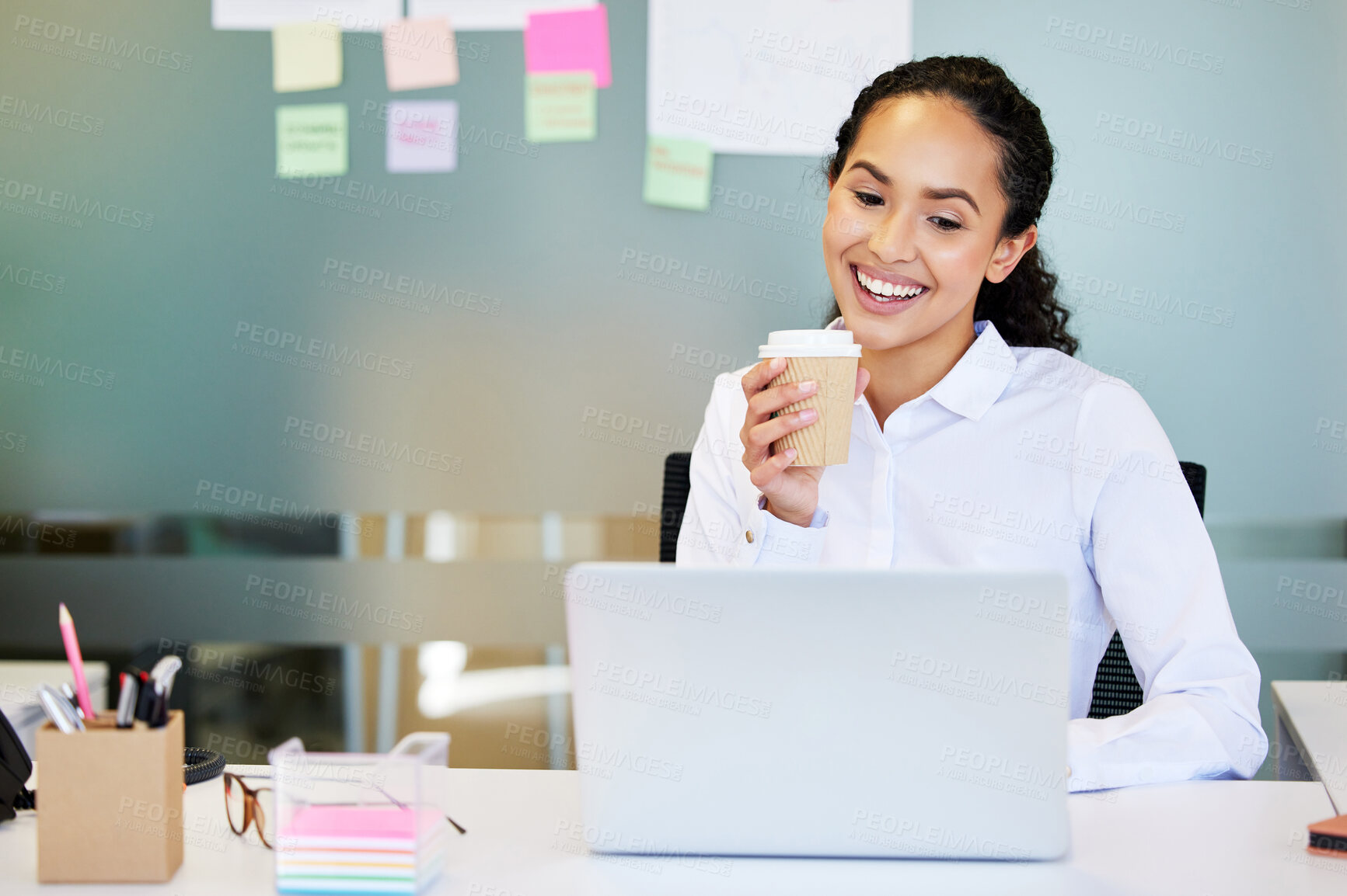 Buy stock photo Shot of an attractive young businesswoman sitting alone in the office and enjoying a coffee while using her laptop