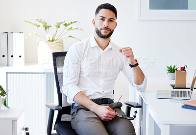 Buy stock photo Shot of a handsome young businessman sitting alone in his office