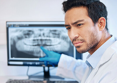 Buy stock photo Shot of a young dentist pointing to an xray of a patients teeth