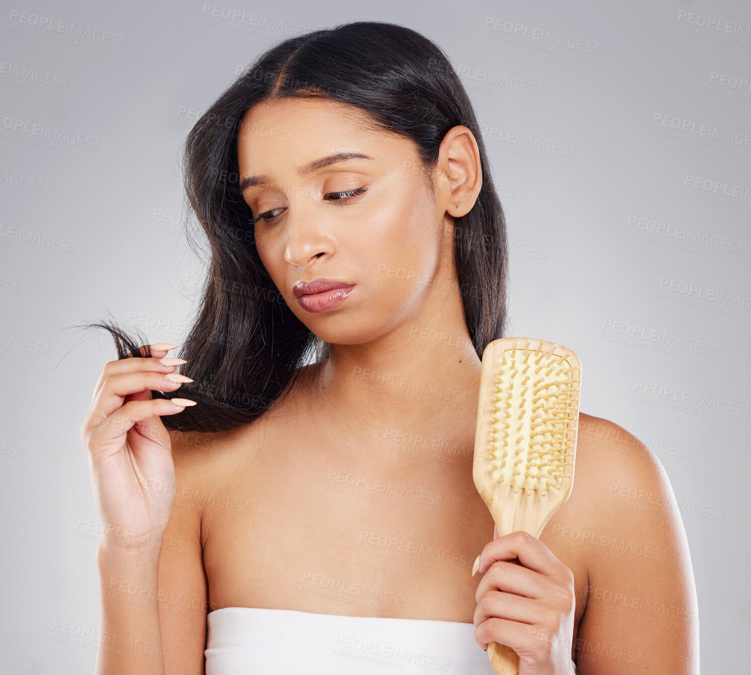 Buy stock photo Cropped shot of an attractive young woman looking unhappy with her hair in studio against a grey background