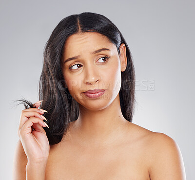 Buy stock photo Cropped shot of an attractive young woman looking unhappy with her hair in studio against a grey background