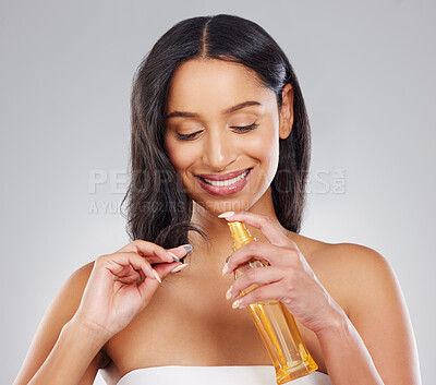 Buy stock photo Cropped shot of an attractive young woman applying treatment to her hair in studio against a grey background