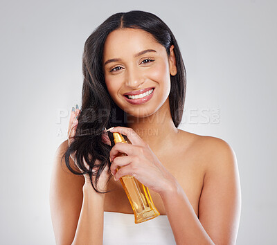 Buy stock photo Cropped portrait of an attractive young woman applying treatment to her hair in studio against a grey background