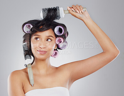 Buy stock photo Cropped shot of an attractive young woman curling her hair against a grey background