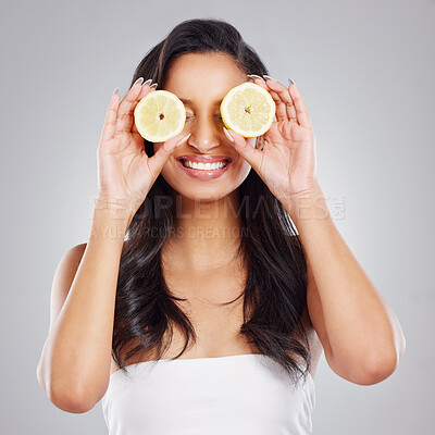 Buy stock photo Cropped shot of an attractive young woman posing with two slices of lemon against a grey background
