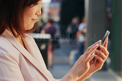 Buy stock photo Shot of a young businesswoman using a smartphone against an urban background