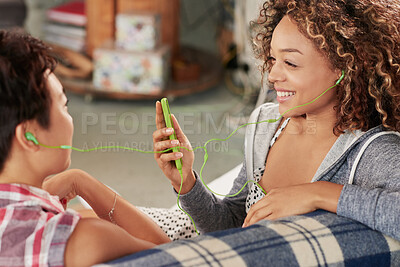 Buy stock photo Women, friends and phone while listening to music on sofa with smile, happiness and home wifi for streaming podcast or radio. Happy female with lesbian partner and media player for entertainment