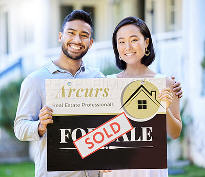 Buy stock photo Shot of a young couple holding up a sold board outside their house