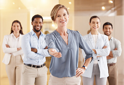 Buy stock photo Portrait of a mature businesswoman extending a handshake in an office with her colleagues in the background