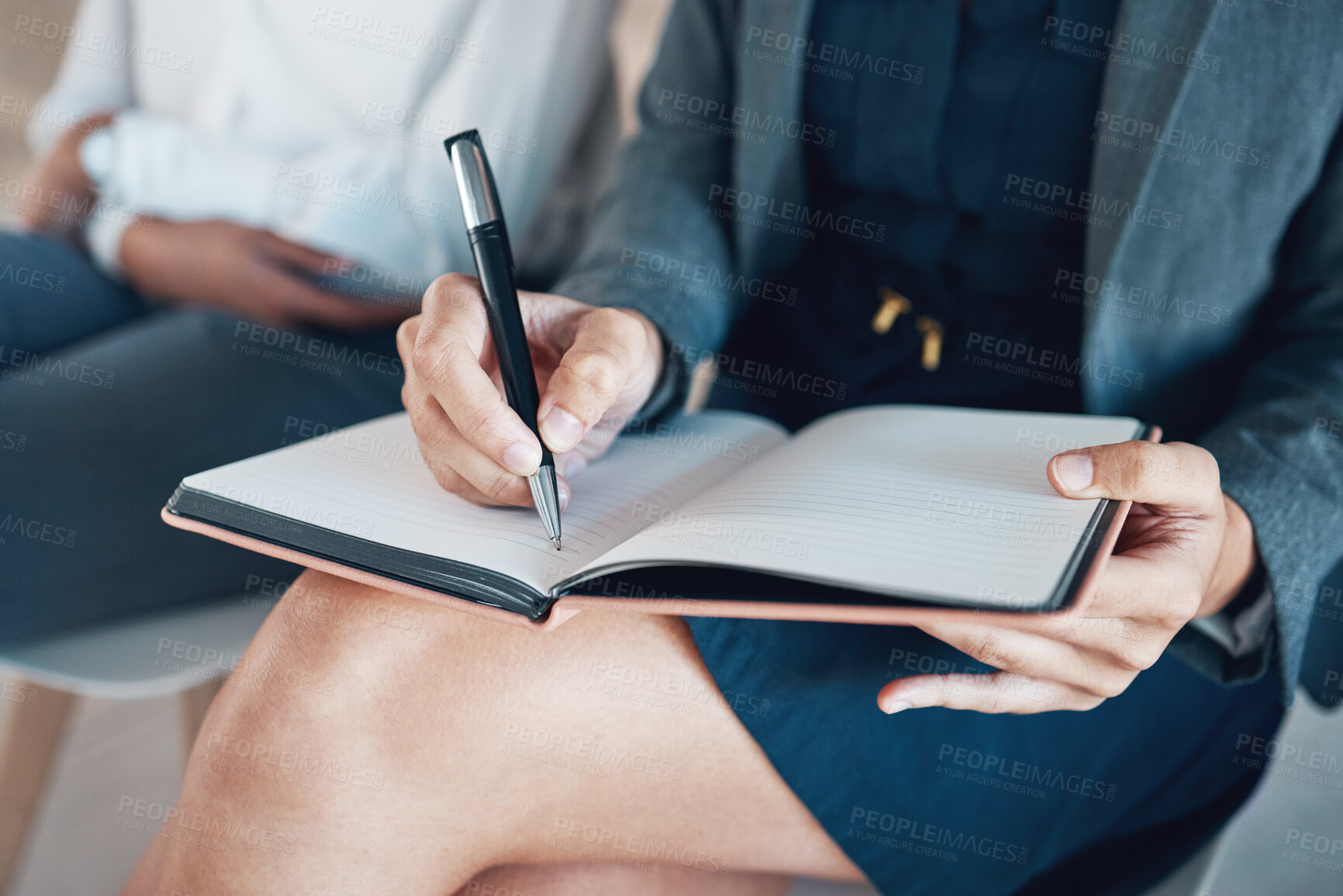 Buy stock photo Cropped shot of an unrecognisable businesswoman sitting with her colleague and writing in a notebook