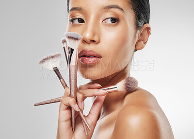 Buy stock photo Studio shot of an attractive young woman holding a collection of makeup brushes against a grey background